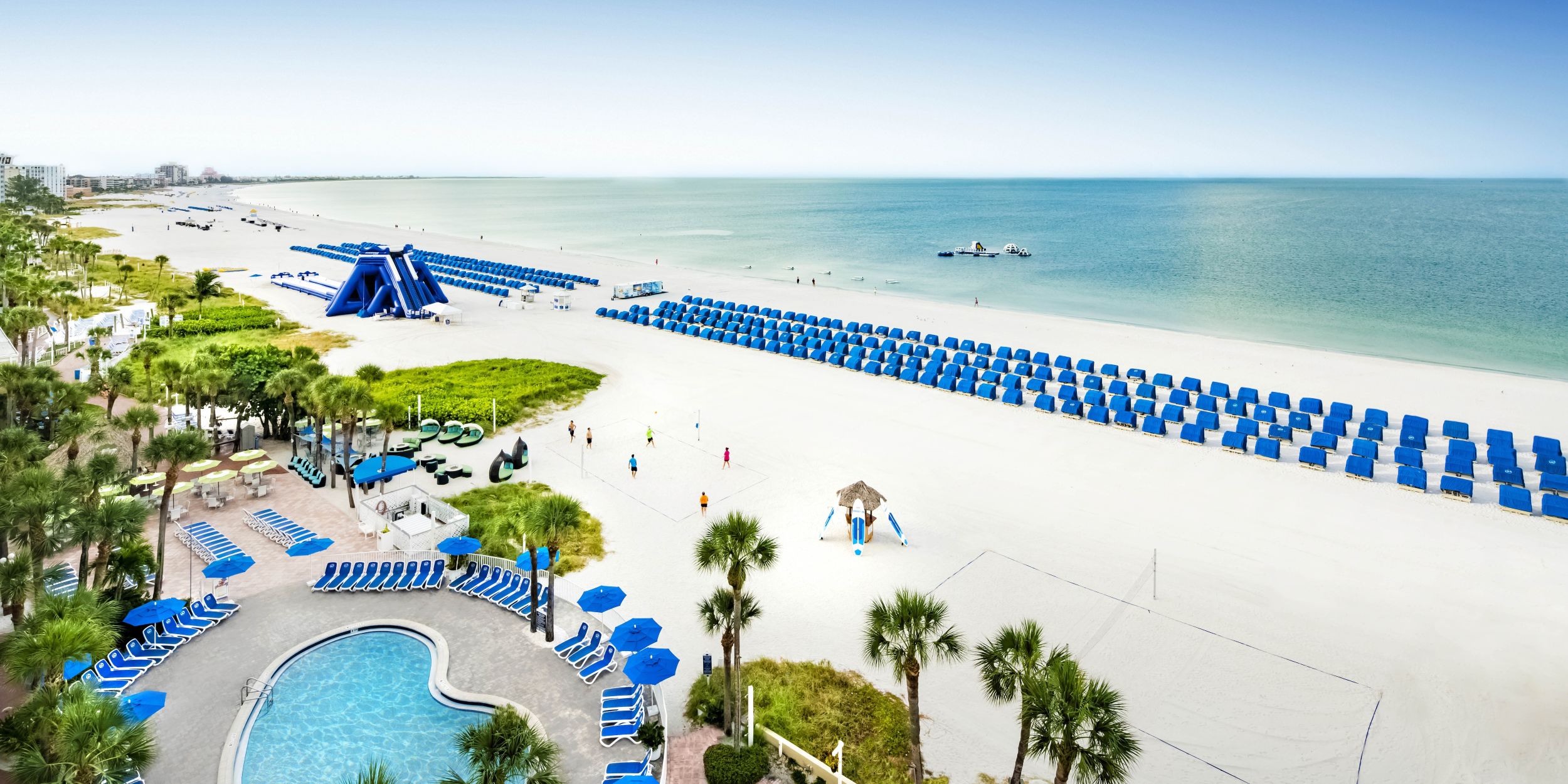 A Beach With A Pool And Umbrellas