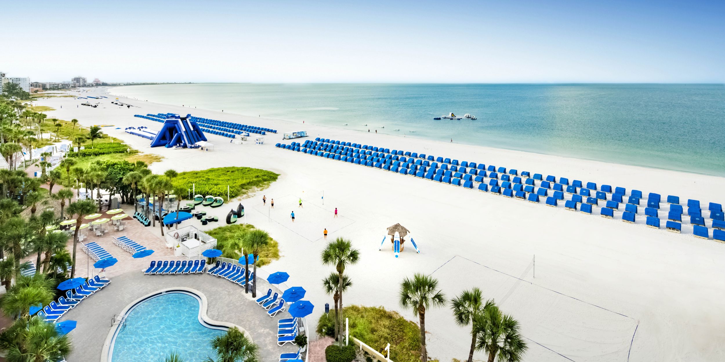 A Beach With A Pool And Umbrellas