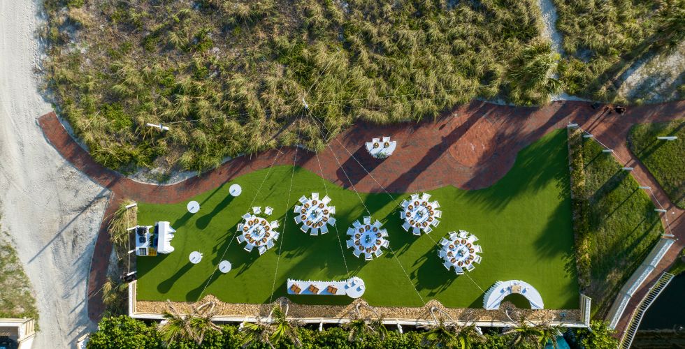 A Large Green Field With A Building And Trees In The Background