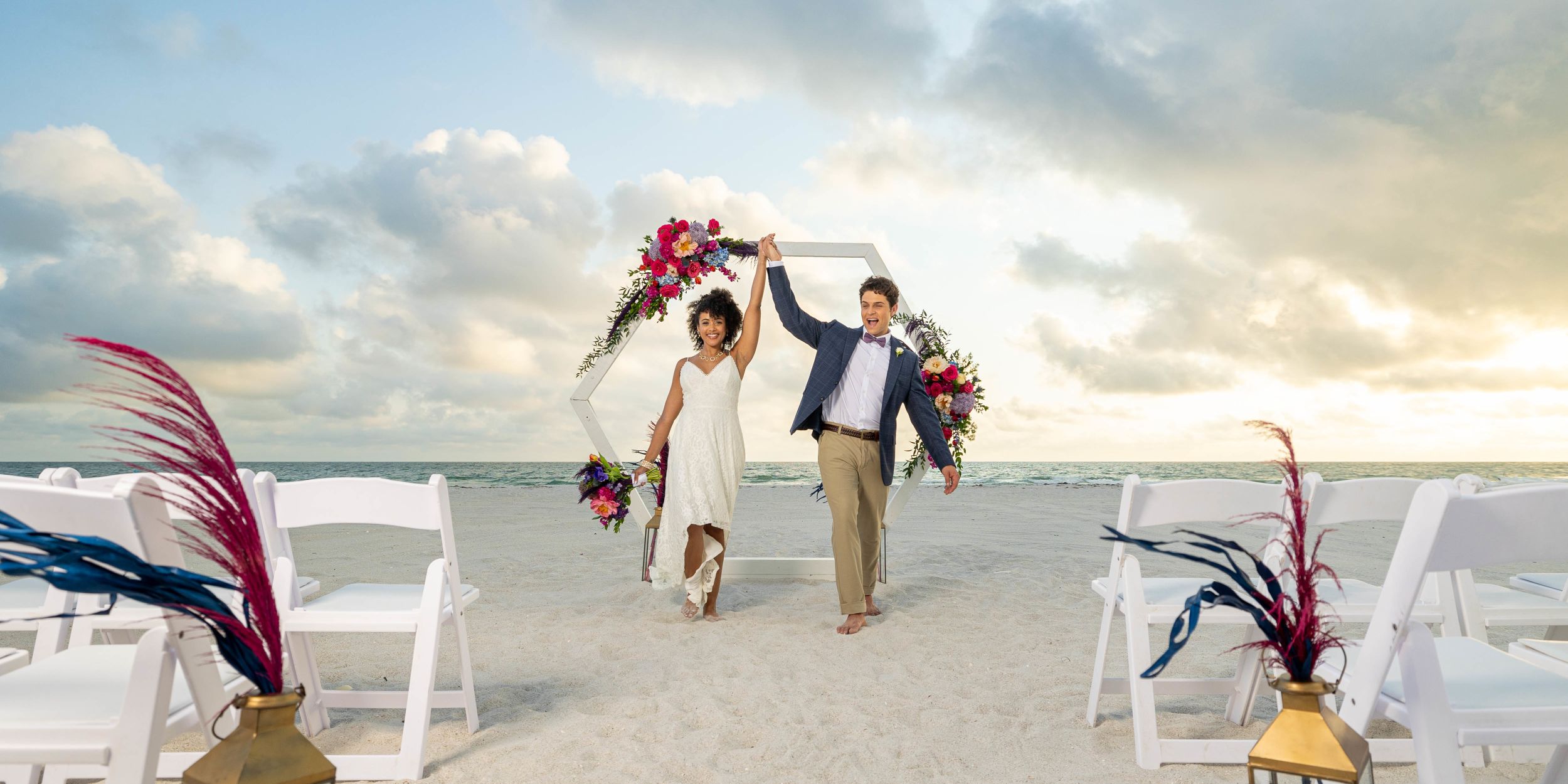 A Man And Woman Holding Flowers On A Beach