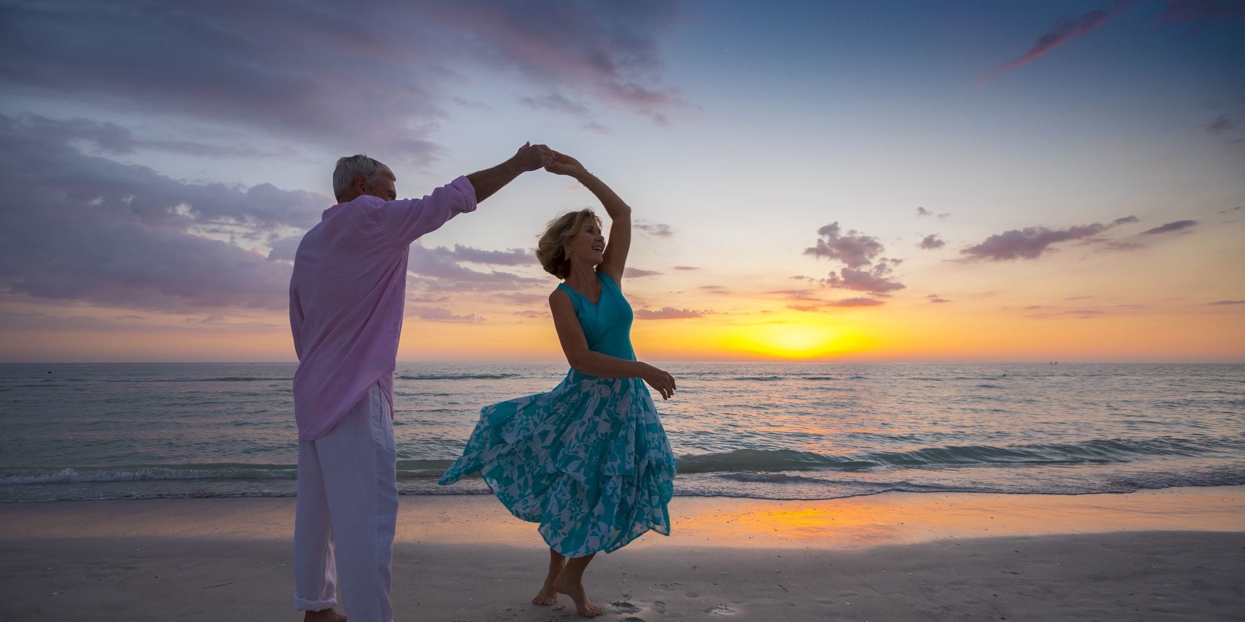 A Man And A Woman Holding Hands On A Beach