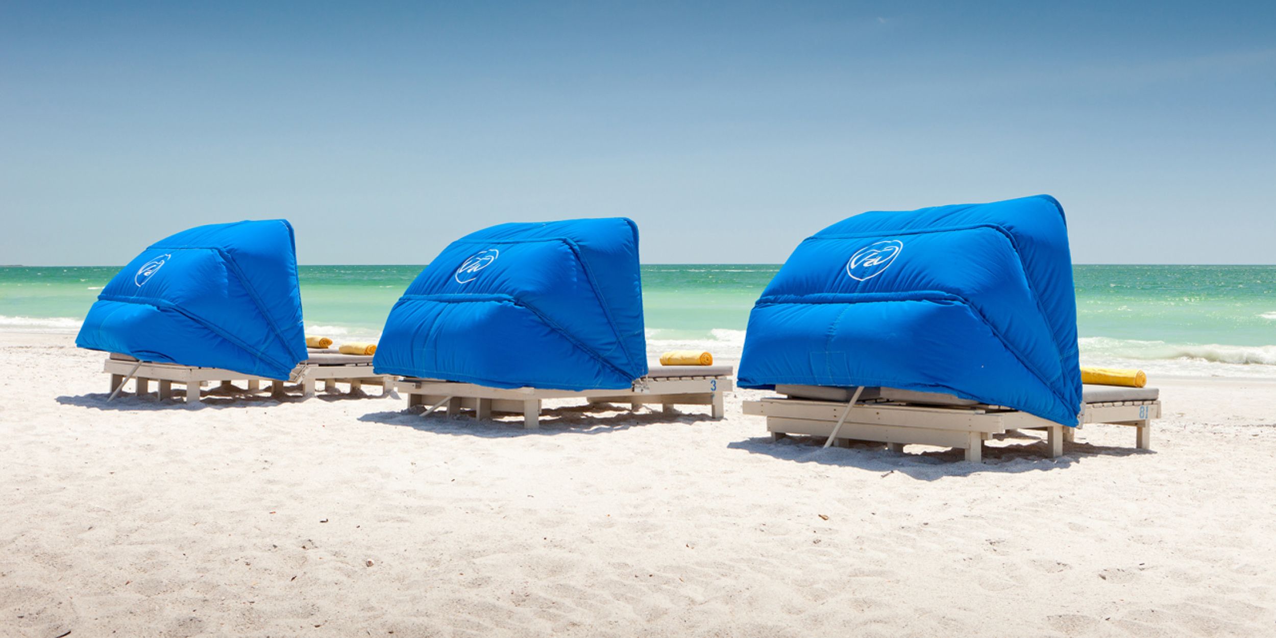 A Flag With A Blue Umbrella Sitting On Top Of A Sandy Beach
