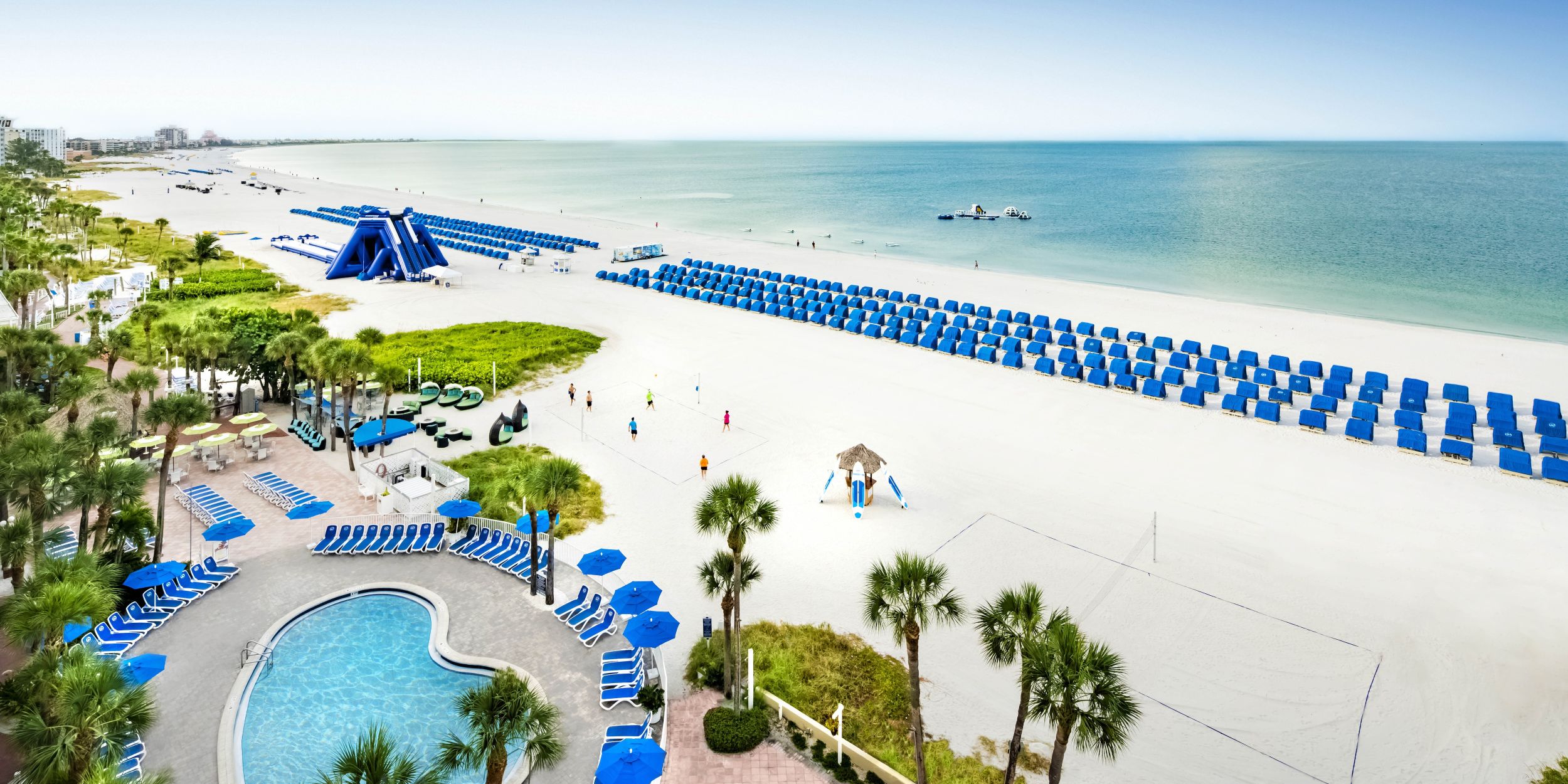A Beach With A Pool And Umbrellas