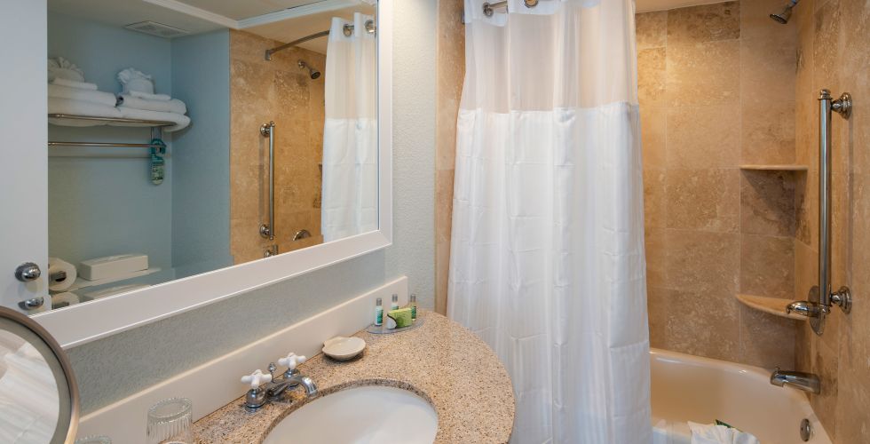 A Rest Room With A Sink And A Mirror