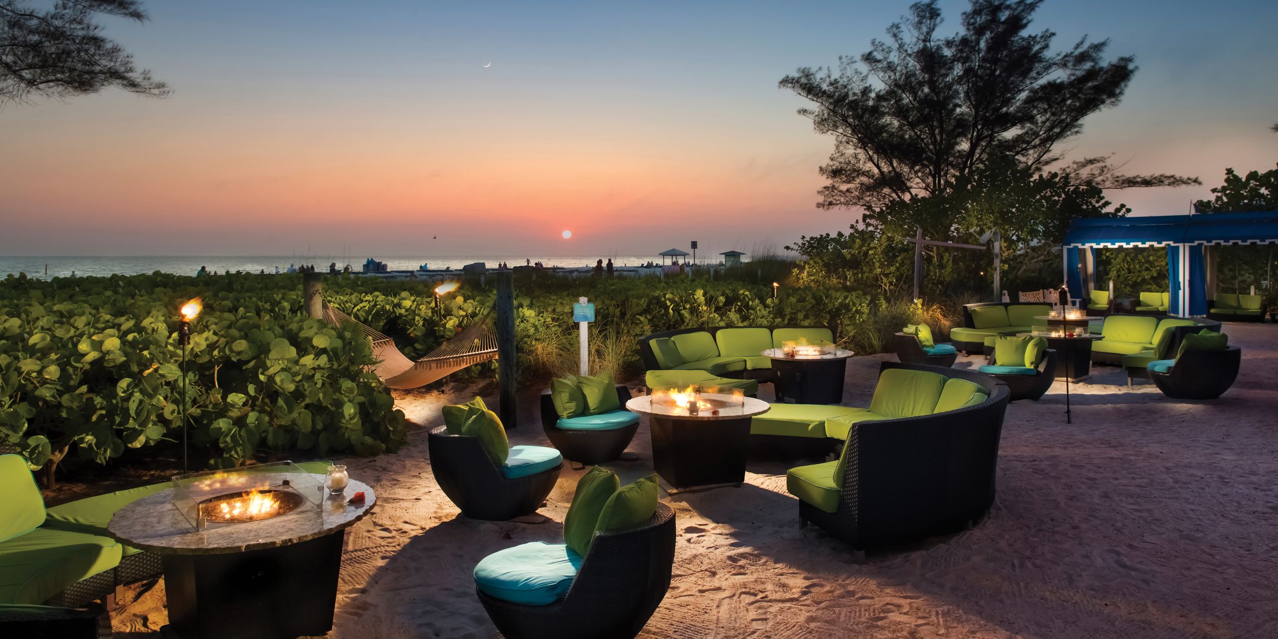 Multiple chairs & tables outside TradeWinds Island Resorts with a sunset view